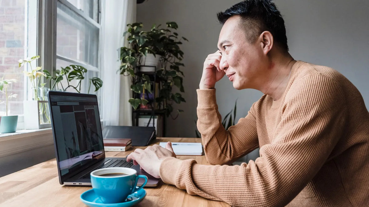 Persona mirando la pantalla de su laptop con gesto de duda en un escritorio sencillo