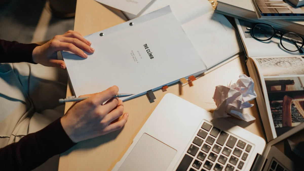 Persona revisando un documento junto a una laptop