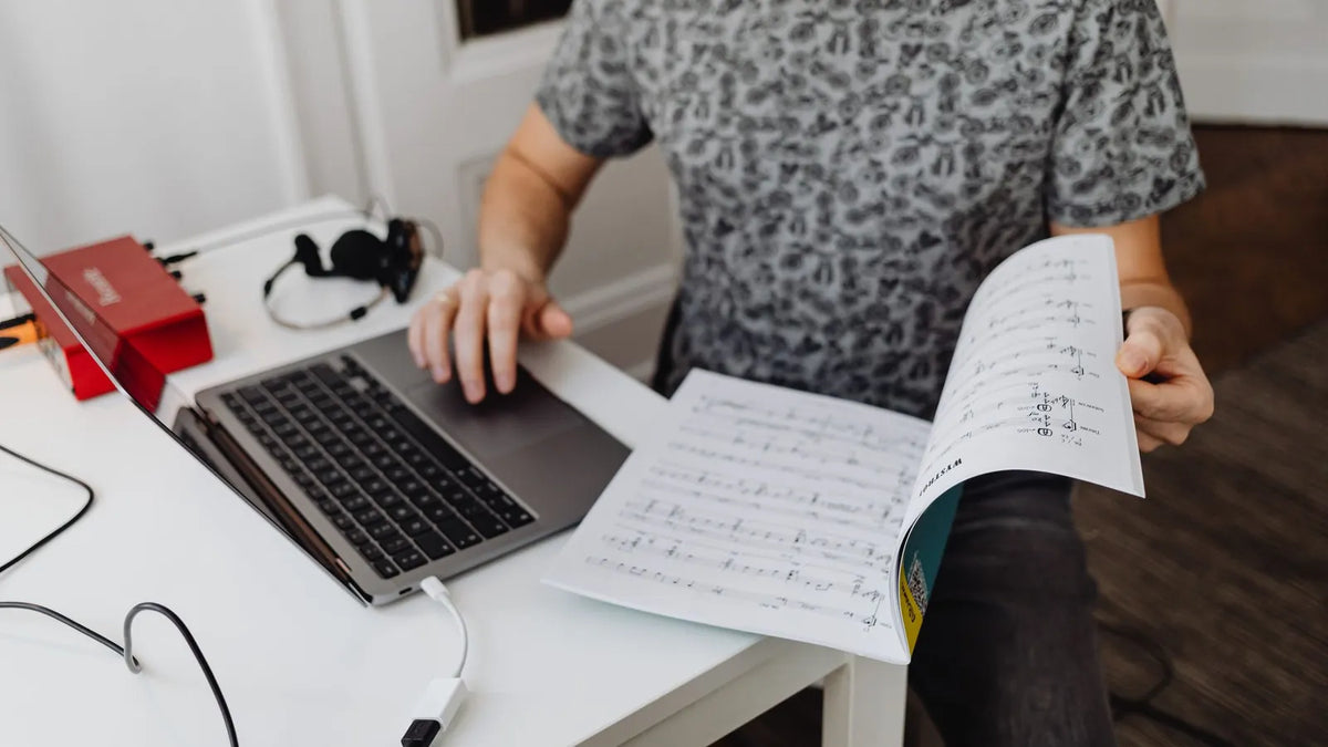 Persona comparando anotaciones frente a una laptop en un escritorio tranquilo
