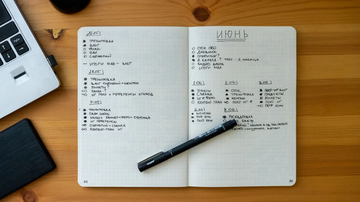 Cuaderno abierto con notas escritas a mano junto a una laptop y un bolígrafo