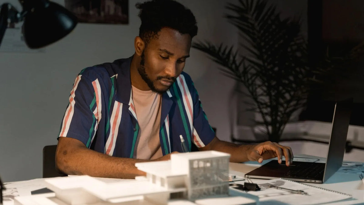 Persona revisando su trabajo en el escritorio junto a una laptop