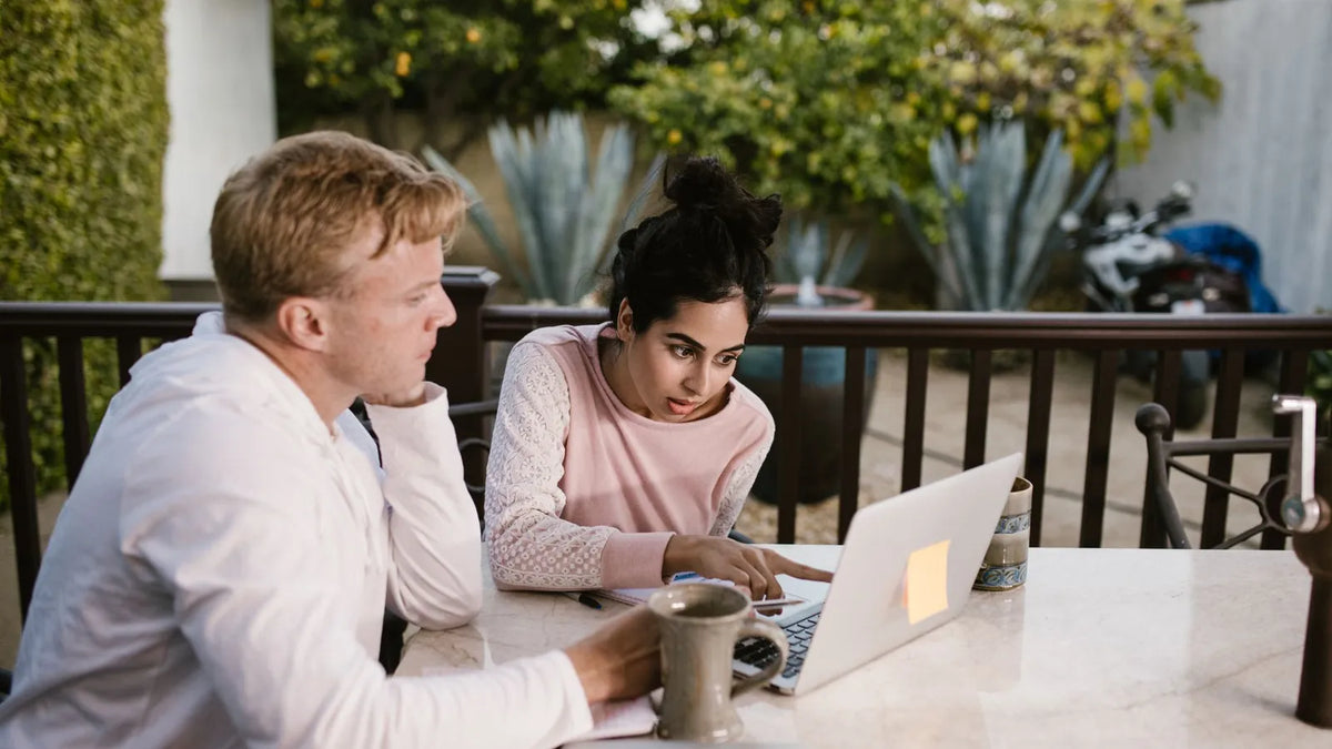 Dos colegas repasando notas juntos en una mesa con una laptop
