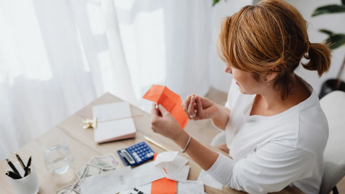 Mujer revisando recibos y cuentas sobre su escritorio