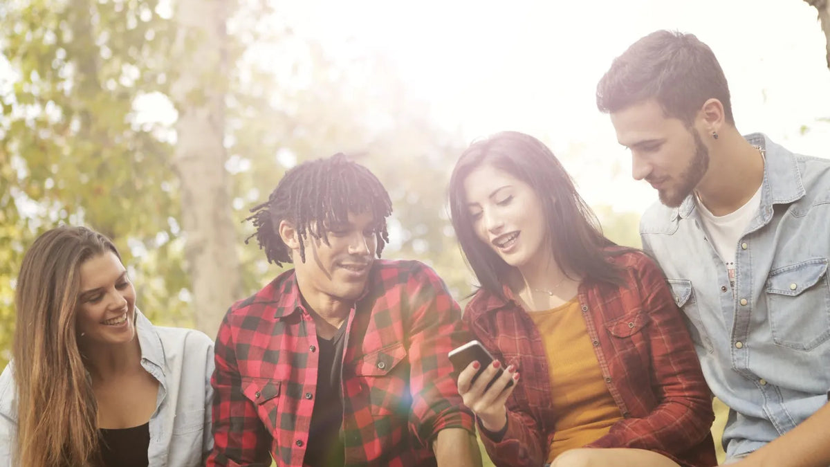 Grupo de amigos mirando juntos la pantalla de un celular