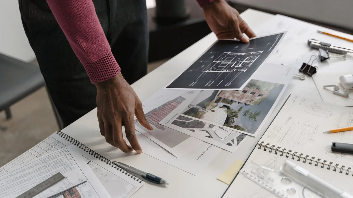 Manos revisando maquetas impresas sobre una mesa de trabajo