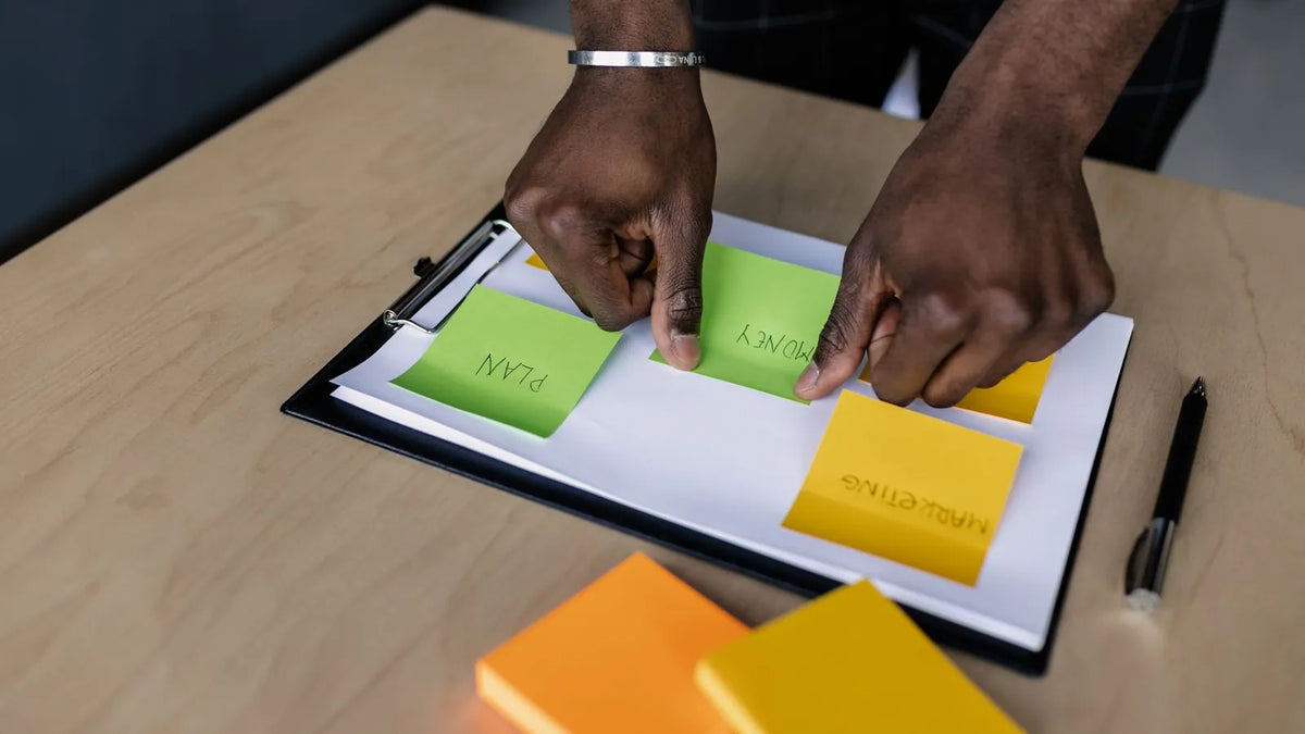 Manos ordenando notas adhesivas sobre una carpeta