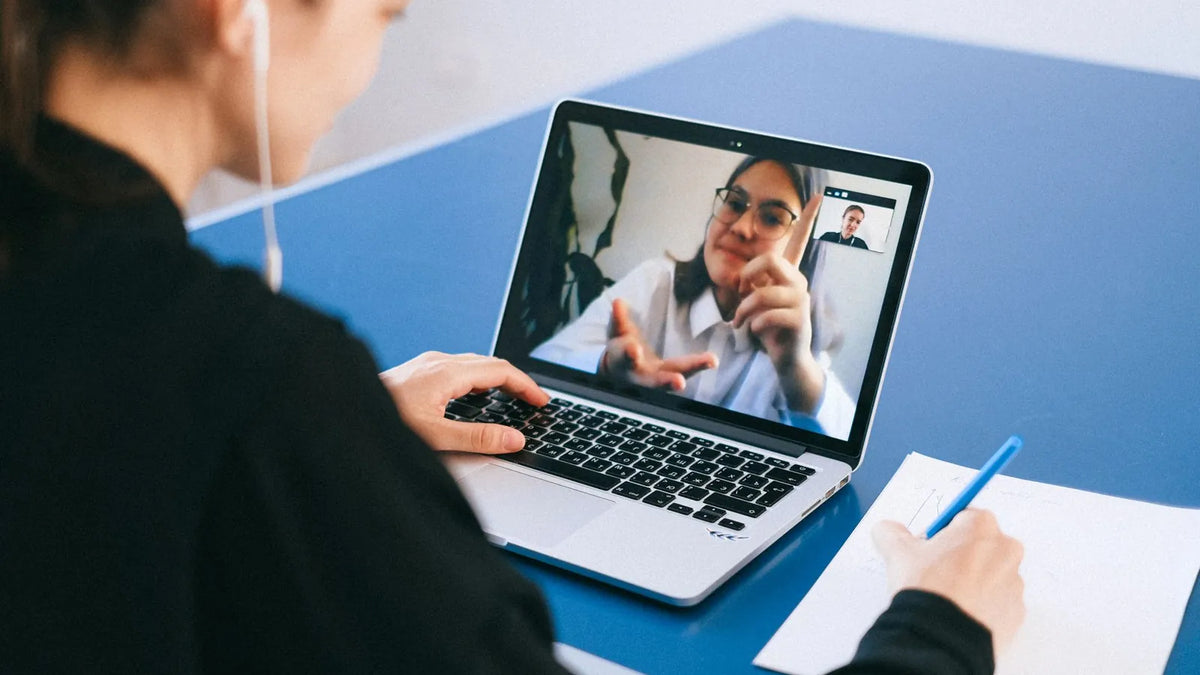 Persona en una videollamada desde su laptop, tomando notas