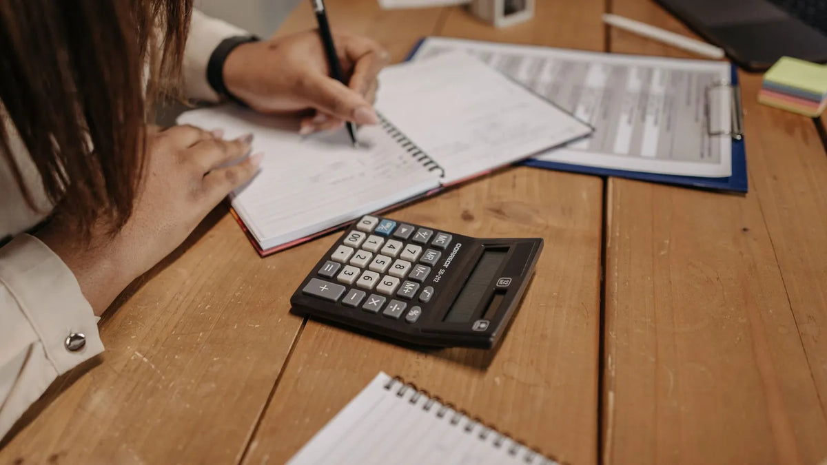 Persona calculando un presupuesto de publicidad con una calculadora y un cuaderno