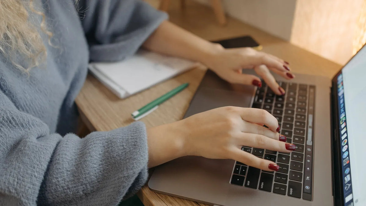Persona escribiendo una búsqueda en una laptop sobre un escritorio