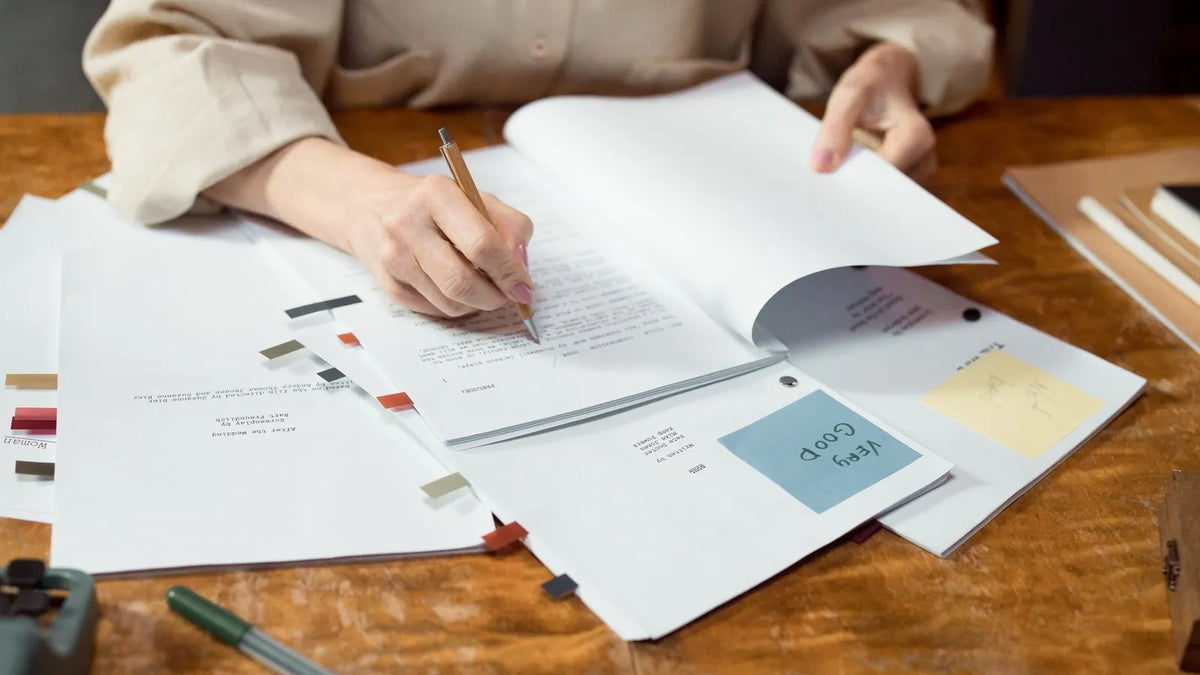 Persona escribiendo a mano en un cuaderno sobre un escritorio de madera