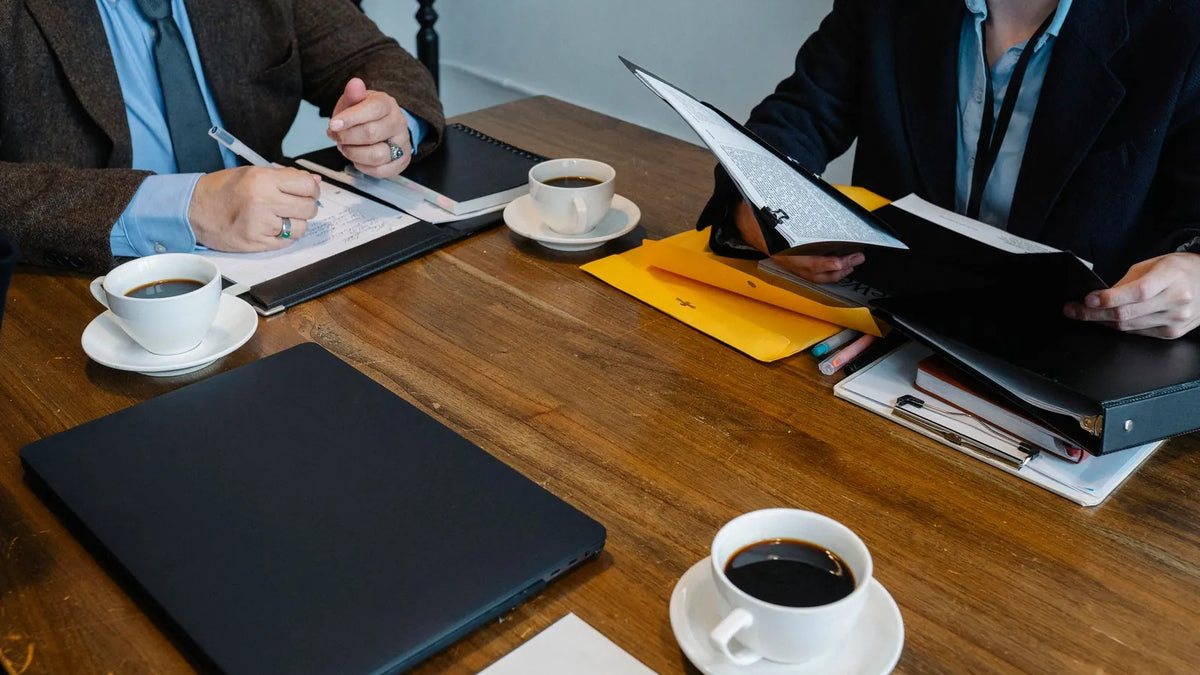 Mesa de reunión con cuadernos, documentos y café