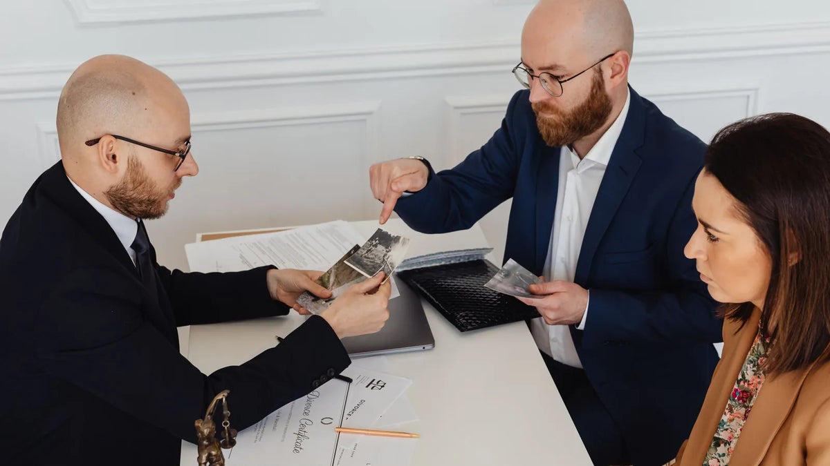 Abogado revisando documentos con dos clientes en una mesa de reuniones
