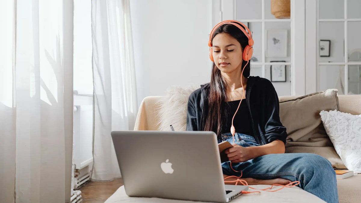 Mujer con audífonos siguiendo una clase en línea desde su laptop