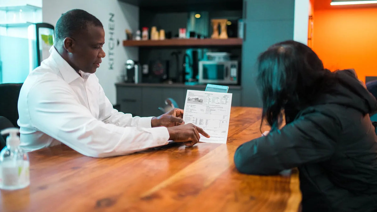 Dos personas en una mesa revisando una lista en papel en una oficina luminosa