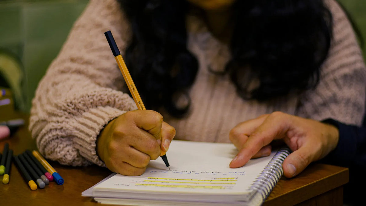 Manos corrigiendo con lápiz un texto impreso sobre un escritorio