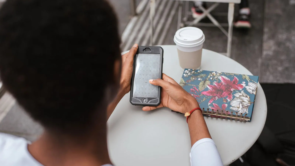 Persona revisando su celular en la mesa de una cafetería