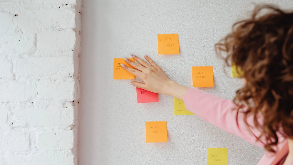 Persona ordenando notas adhesivas sobre una pared