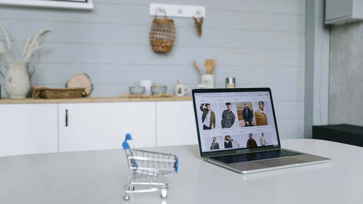 Carrito de compras en miniatura junto a una laptop con una tienda online abierta