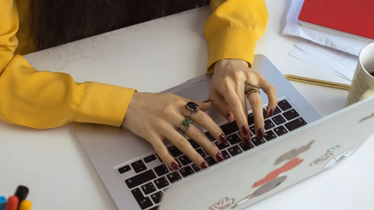 Persona escribiendo una búsqueda en una laptop sobre un escritorio sencillo