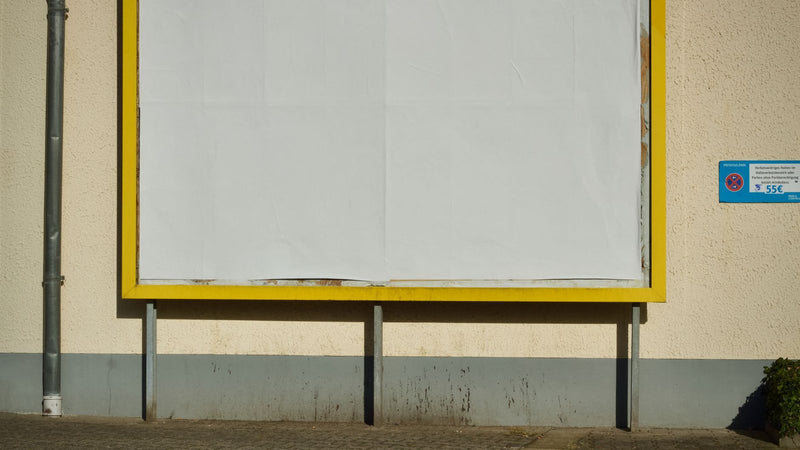 Cartel publicitario vacío con marco amarillo en una calle