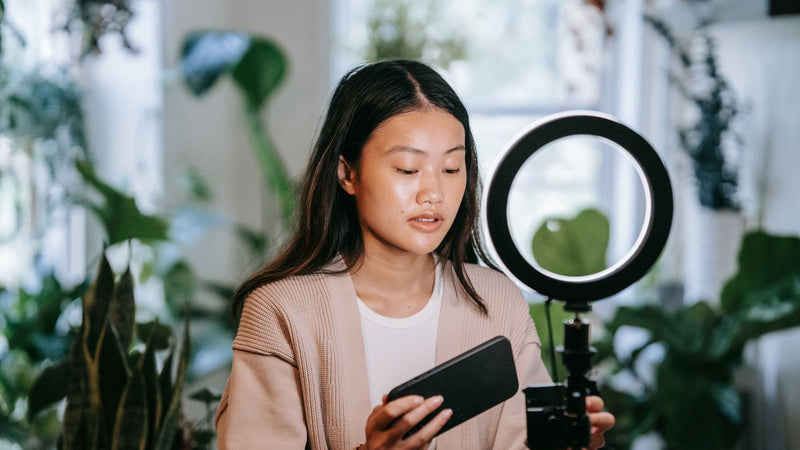 Mujer grabando un video con su celular y un aro de luz