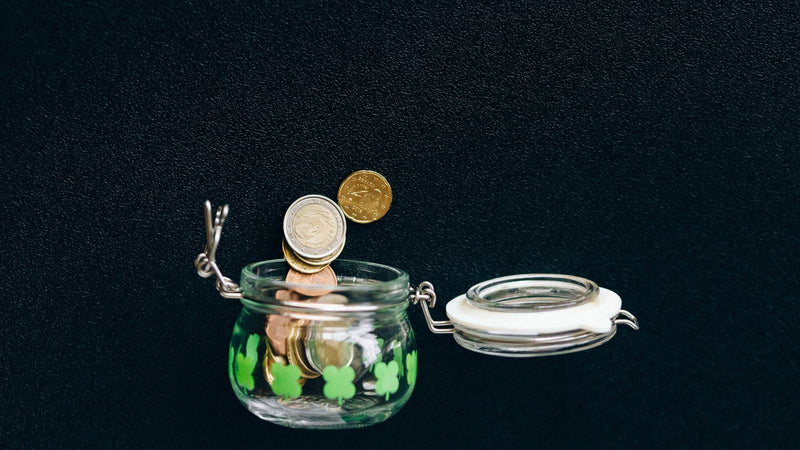Frasco abierto con monedas sobre fondo oscuro
