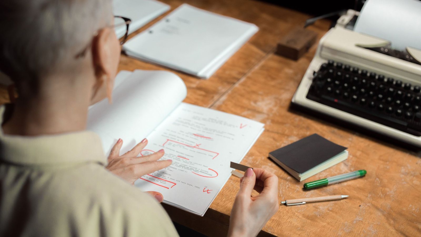 Persona corrigiendo un texto impreso con marcas rojas