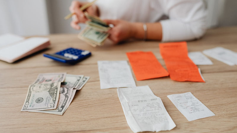 Manos contando billetes junto a recibos y una calculadora