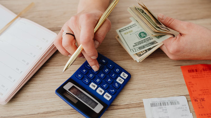 Manos con una calculadora, billetes y un cuaderno