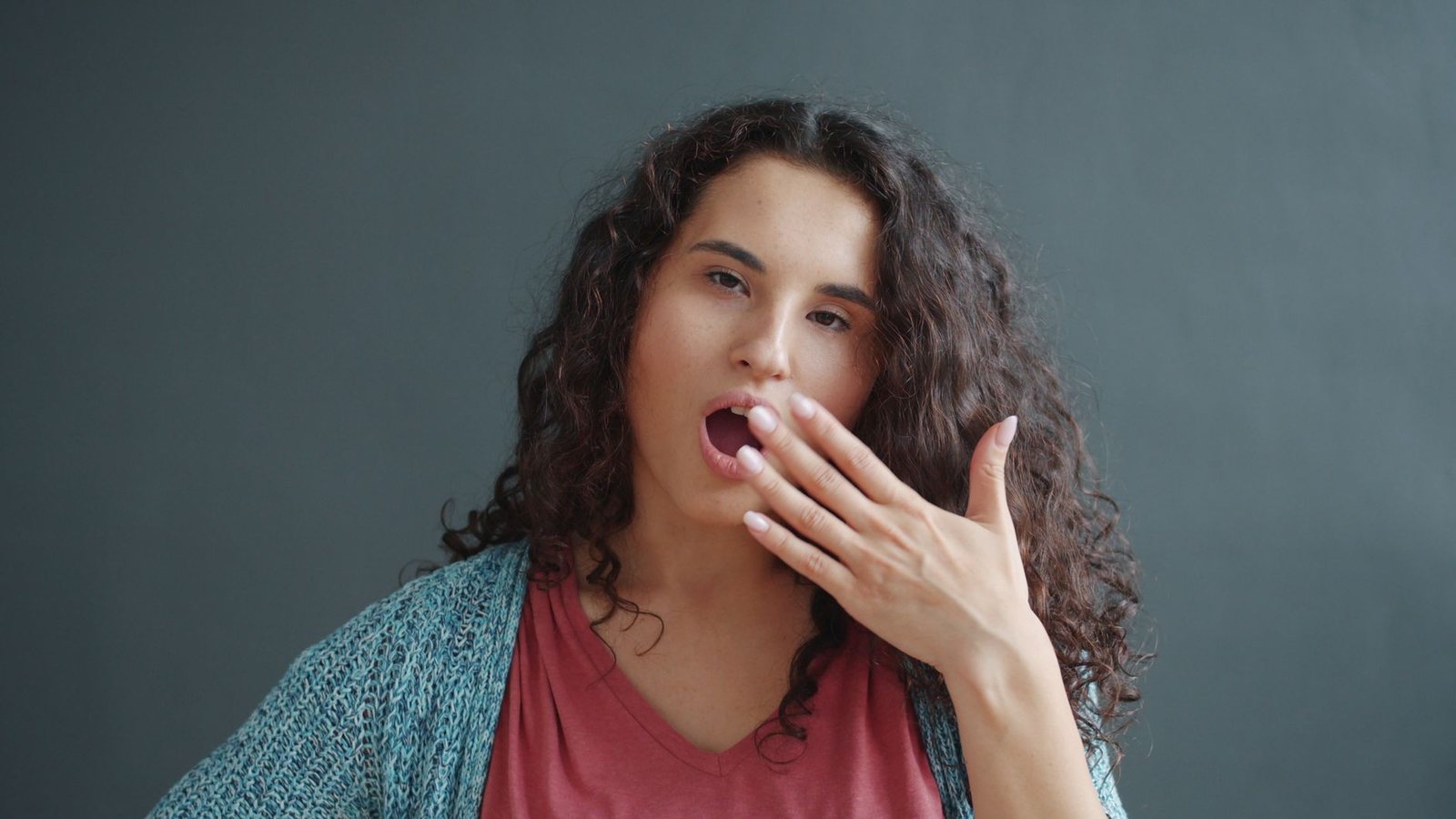 Mujer bostezando con la mano en la boca