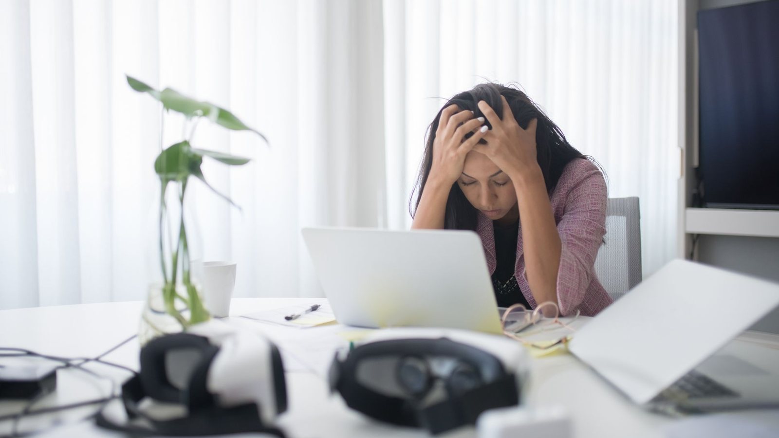 Mujer agobiada con las manos en la cabeza frente a su laptop