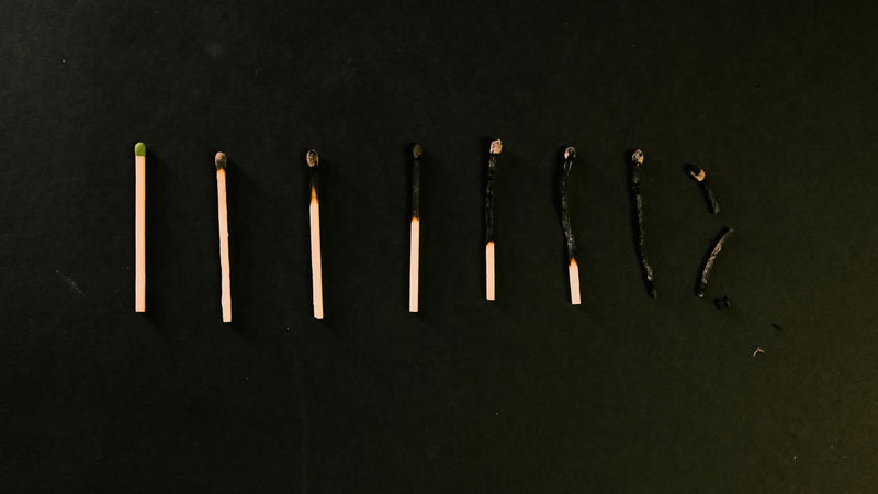 Fila de fósforos que se van quemando sobre fondo negro